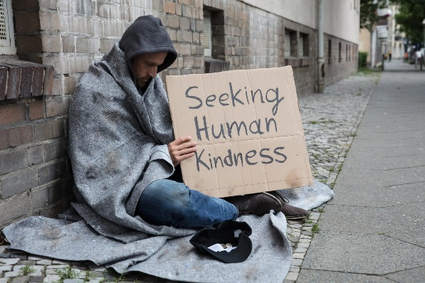 Seated man with sign: Seeking Human Kindness